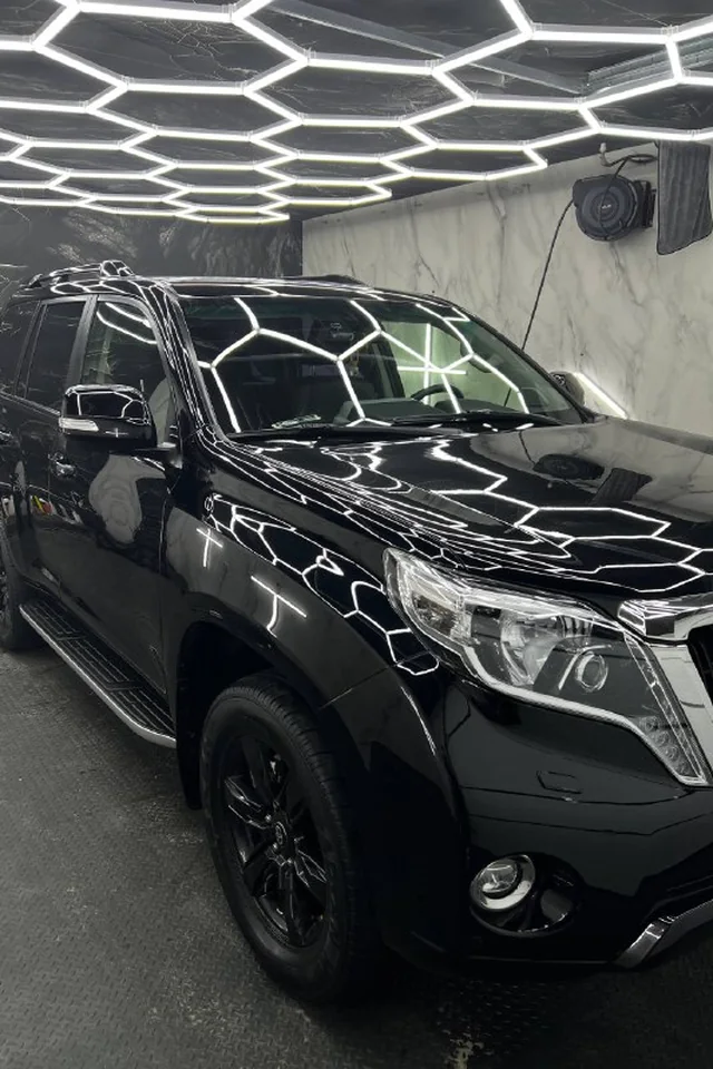 Чёрный Toyota Land Cruiser Prado с оклеенными фарами в боксе Just Point Car